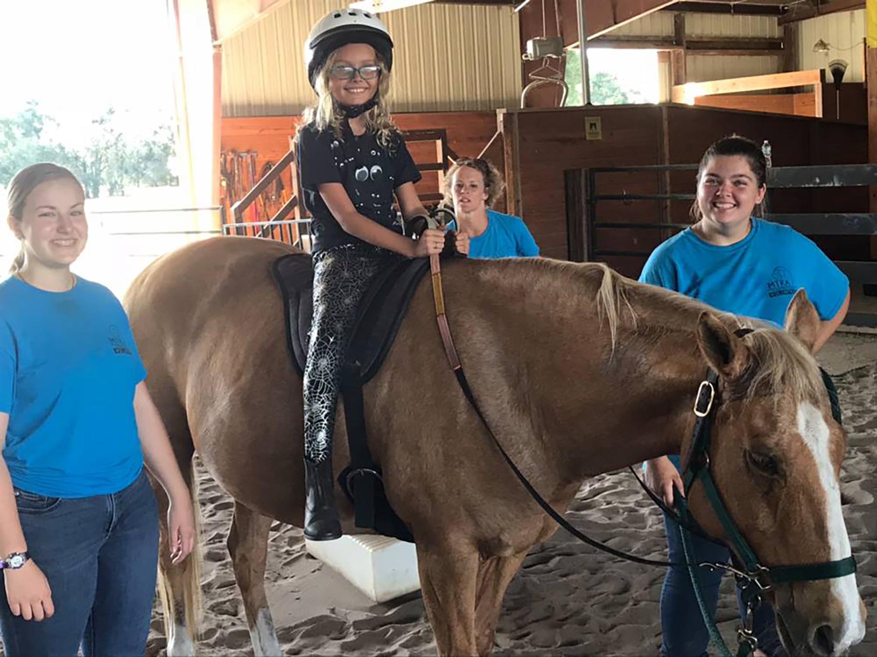 Young rider on a horse with MTRA volunteers in an arena